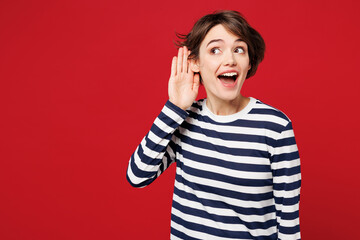 Young curious nosy smiling happy woman she wear blue striped sweatshirt casual clothes try to hear...
