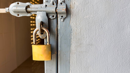 A shiny golden locking pad on a textured gray metal door, symbolizing security, protection, and reliability, creating a contrast between the key's elegance and the rugged door surface