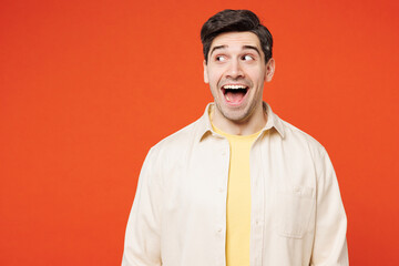 Young shocked surprised fun overjoyed happy man he wear white shirt yellow t-shirt casual clothes look aside on area mockup isolated on plain red orange background studio portrait. Lifestyle concept.