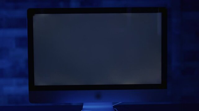 Close up on blank computer screen in dimly lit room