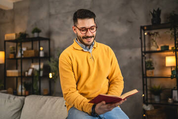 young adult man with eyeglasses read a book at home