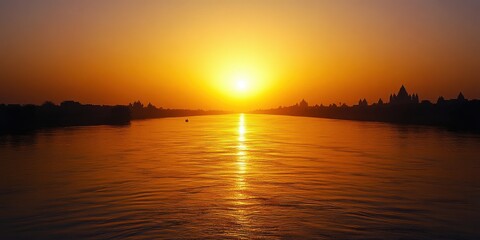 Naklejka premium A serene sunset over a tranquil river, casting a warm orange glow across the water's surface.