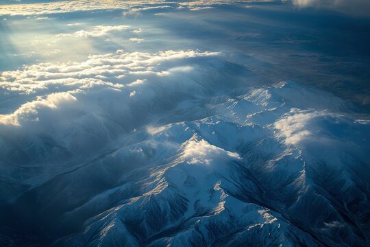 A high-angle shot of snowy mountains covered with clouds during a dark evening 