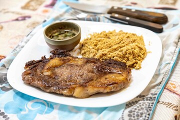 Typical Brazilian lunch with grilled steak, farofa and sauce