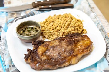Typical Brazilian lunch with grilled steak, farofa and sauce
