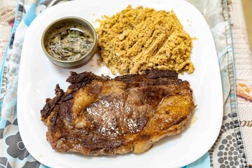 Typical Brazilian lunch with grilled steak, farofa and sauce