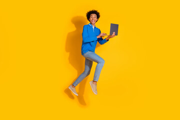 Full size photo of pretty young male working netbook running wear trendy blue outfit isolated on yellow color background