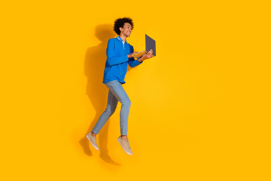 Full body photo of attractive young man netbook running dressed stylish blue clothes isolated on yellow color background