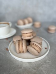 Chocolate Macarons with Coffee Cream Filling on Ceramic Plate