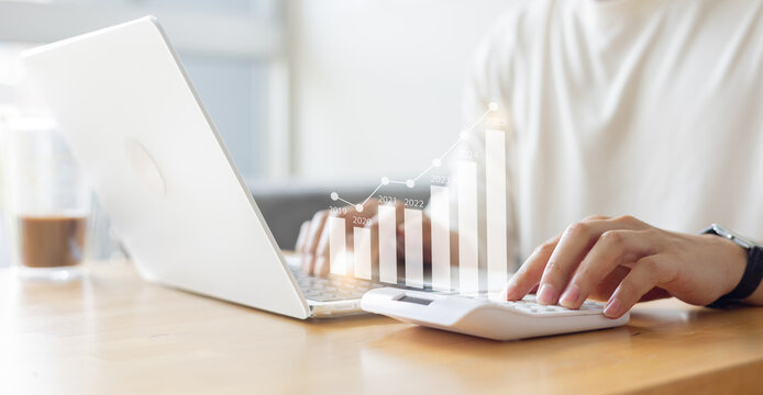 close up young businessman hand press calculator and work on laptop to calculate and forecasting profit about business trend of new year 2025 for goal and achievement concept