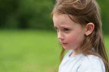 Little red-haired cute girl in summer outdoors in park. Concept of active healthy child in nature