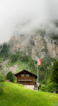 Scenic Swiss chalet beneath misty alpine cliffs at Lac de Taney