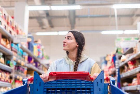 Woman with shopping cart looking away in supermarket