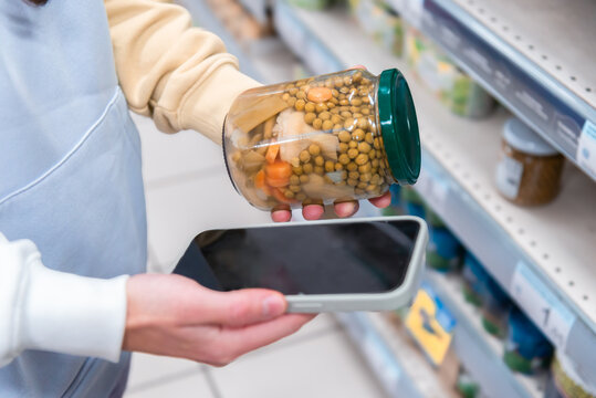 Woman checking smartphone while shopping in supermarket