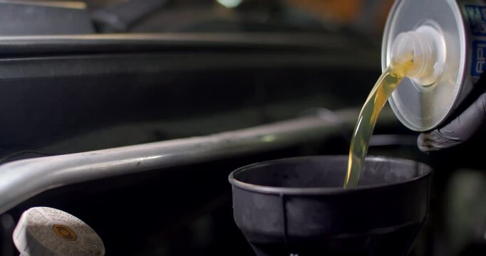Add new engine oil to the engine.Change new oil to the car engine.New engine oil golden yellow.