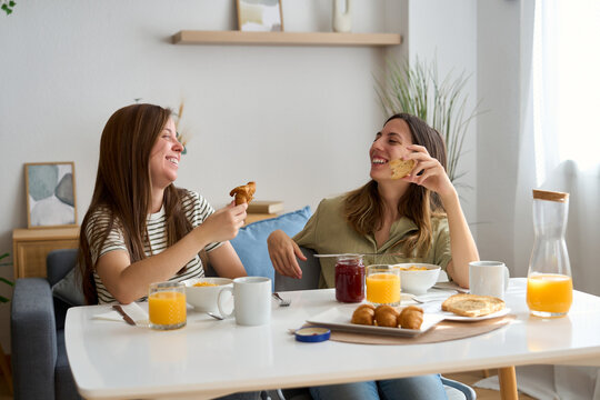 Lesbian couple enjoying breakfast together in cozy home setting - Powered by Adobe