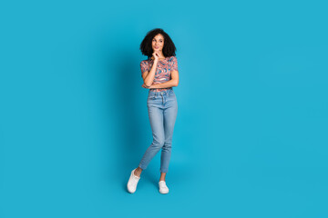 Young woman in a colorful t-shirt and jeans poses against a blue background, exuding a sense of style and fashion