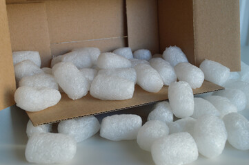 Cardboard Box with Protective Packaging for Shipping Goods. A cardboard shipping box filled with protective packaging materials, including eco-friendly paper padding and biodegradable packing peanuts.