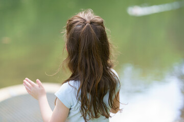 Little cute sad girl walking in summer park. Concept of sad child outdoors