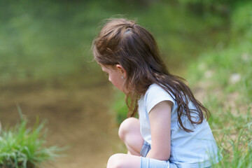 Obraz premium Little cute sad girl walking in summer park. Concept of sad child outdoors