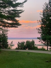 This photo captures a beautiful sunset over a tranquil body of water, with the sky painted in shades of pink, orange, and purple.