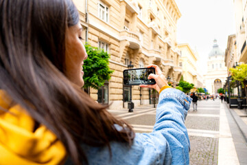 Young woman tourist capturing the city's skyline with her camera during her travels
