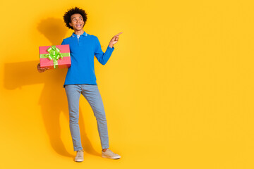 Full size photo of nice young man giftbox indicate finger empty space isolated on yellow color background