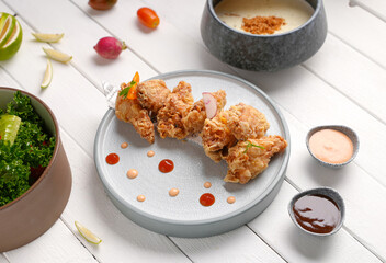 Crispy fried chicken with sauce and salad side and Mushroom soup bowl, white wood background