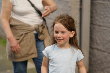 Fototapeta premium Little cute smiling girl outdoors with her grandma. Healthy active child concept