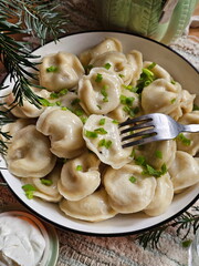 Dumplings with sour cream on a wooden table