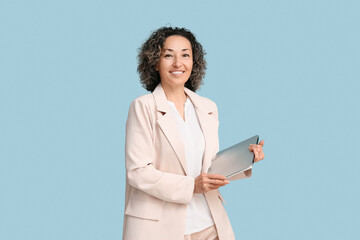 Mature businesswoman with modern laptop on blue background