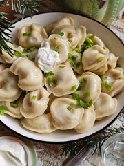 Dumplings with sour cream on a wooden table
