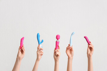 Female hands with different vibrators on white background