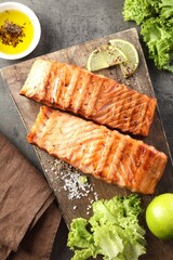 Delicious grilled salmon fillets served on grey textured table, flat lay