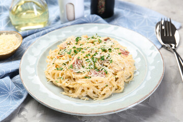 Delicious pasta Carbonara with bacon served on gray textured table, closeup
