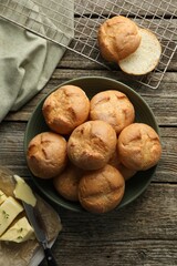 Homemade tasty buns, butter and knife on wooden table, flat lay