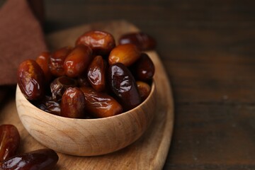 Tasty sweet dried dates in bowl on wooden table, closeup. Space for text