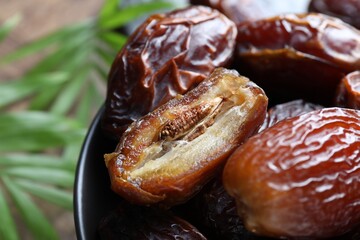 Tasty dried dates in bowl on table, closeup