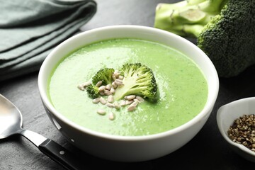Delicious broccoli cream soup served on black table, closeup