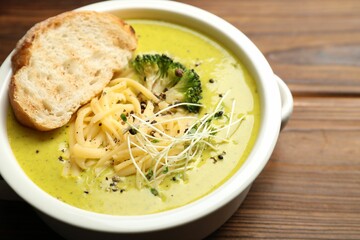 Delicious broccoli cream soup and crouton in bowl on wooden table, closeup