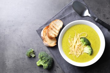 Delicious broccoli cream soup served on gray textured table, flat lay. Space for text