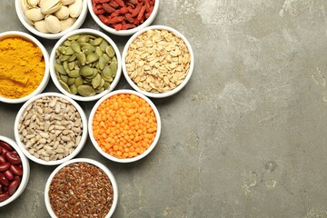 Different superfoods in bowls on grey table, flat lay. Space for text