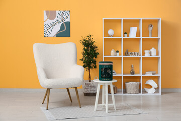 Portable table fan with humidifier on coffee table and armchair near orange wall in room