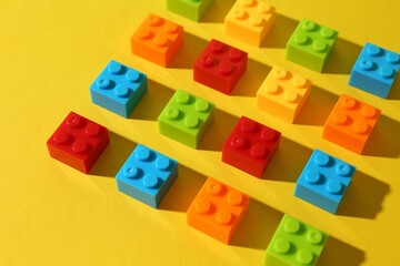 Obraz premium Construction toy. Colorful building bricks on yellow background, closeup
