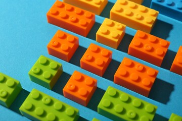 Naklejka premium Construction toy. Colorful building bricks on light blue background, closeup