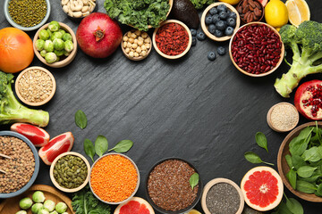 Frame of different superfood products on black table, flat lay. Space for text