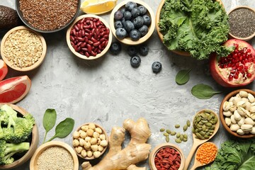Frame of different superfood products on grey table, flat lay. Space for text