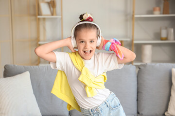 Little girl in headphones listening to music at home