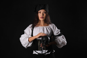 Beautiful young Asian woman dressed as pirate with human skull on black background