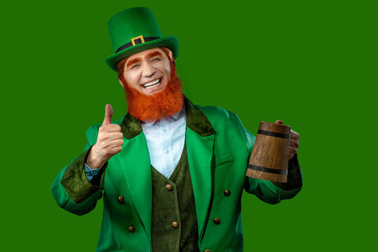Leprechaun elf on St. Patrick's Day. Cheerful character Irish leprechaun for advertising with a red natural beard in a green suit and green hat for advertising. Cosplay at the festival on March 17th